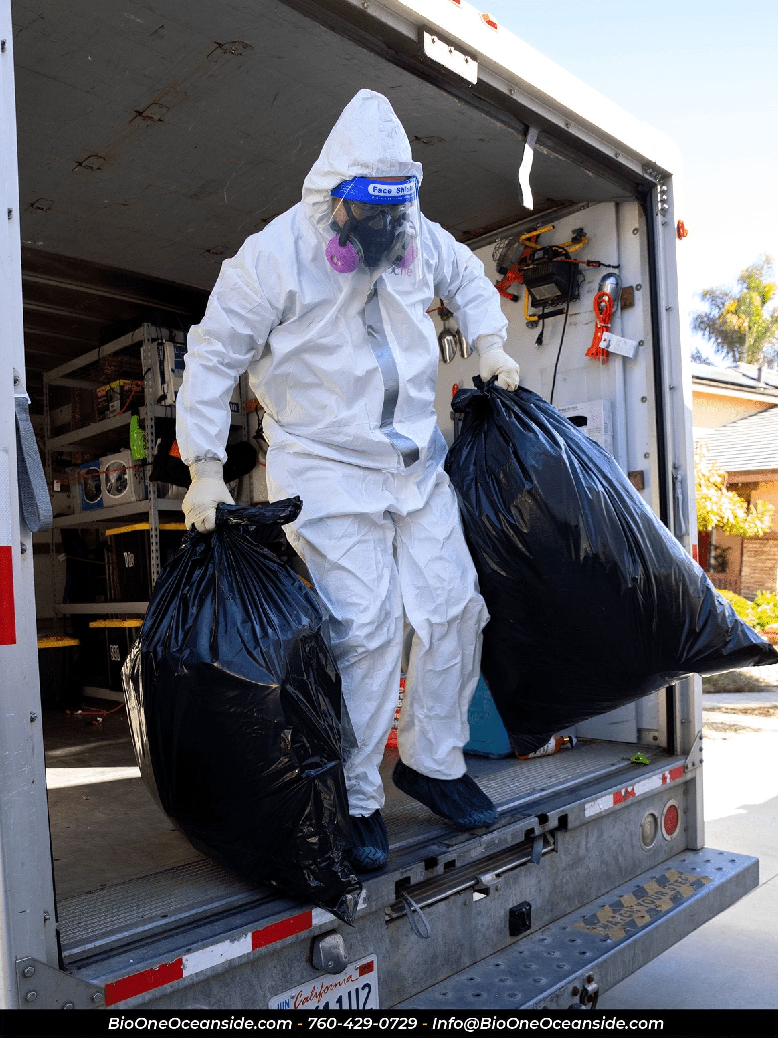 Image shows Bio-One technician carrying out two bags of trash and waste.