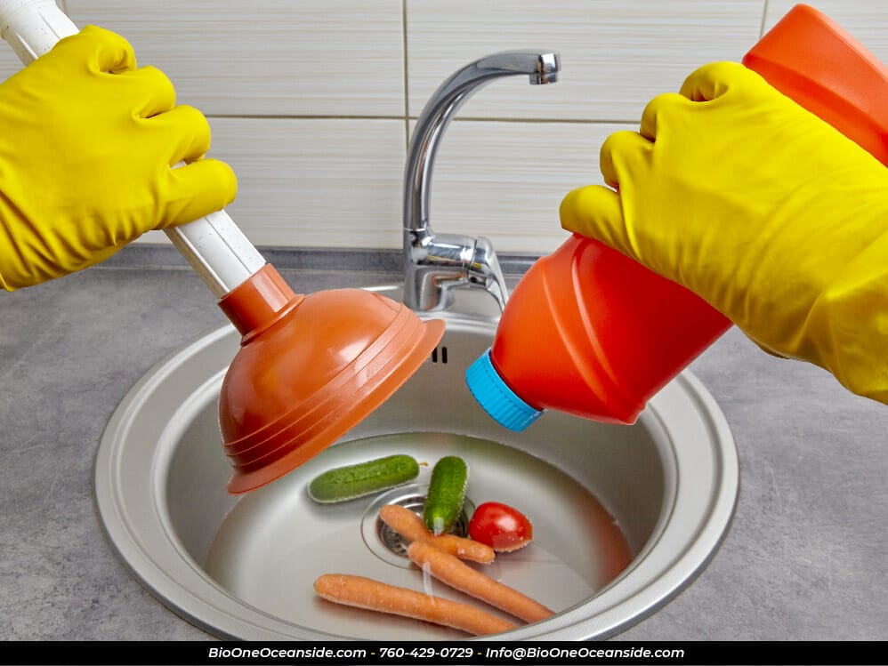 Rubber gloves hold a plunger and a pipe cleaner. Photo credit: @onebit14 - Freepik.